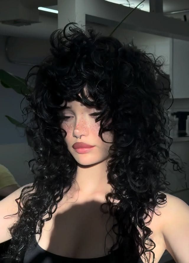 2C Curly Hairstyles: 10 Ideas for Layers, Buns and Bangs 5 Woman with voluminous long black curly hair and bangs posing indoors