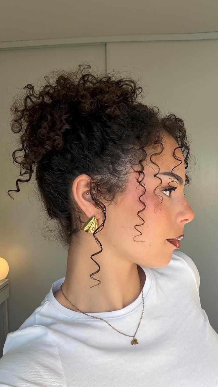 2C Curly Hairstyles: 10 Ideas for Layers, Buns and Bangs 8 Woman with dark brown curly hair styled in a high bun and ringlets.