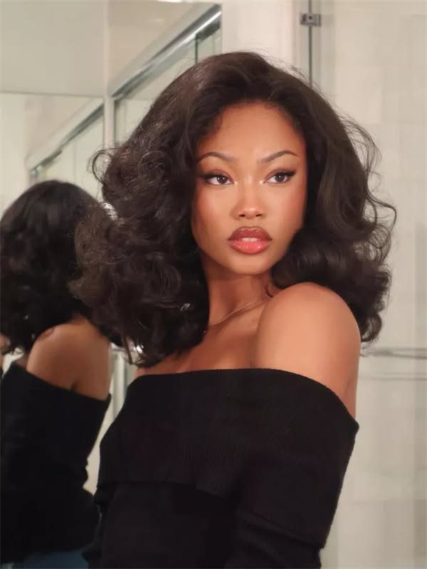 4C Hair Blown Out with Braids, Buns and Waves: 9 Ideas 3 Woman with voluminous curly dark brown blowout hair wearing a black off-the-shoulder top.