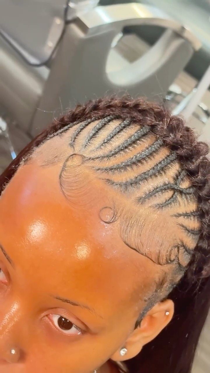 Intricate cornrow braids and a braided crown on a person's dark hair.