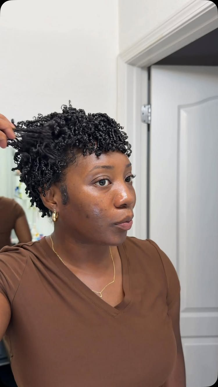 Woman with short curly black hair wearing a brown shirt in a room