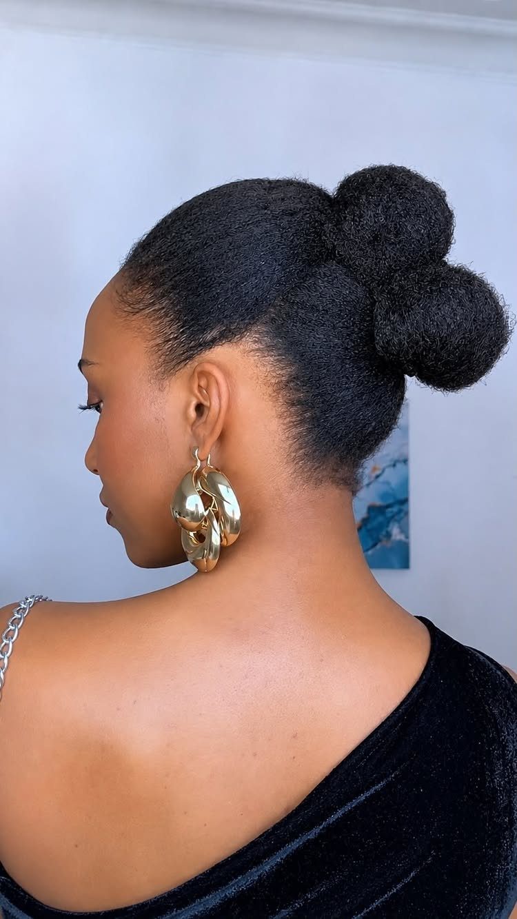 Woman with natural 4C hair styled in two stacked buns at the back.