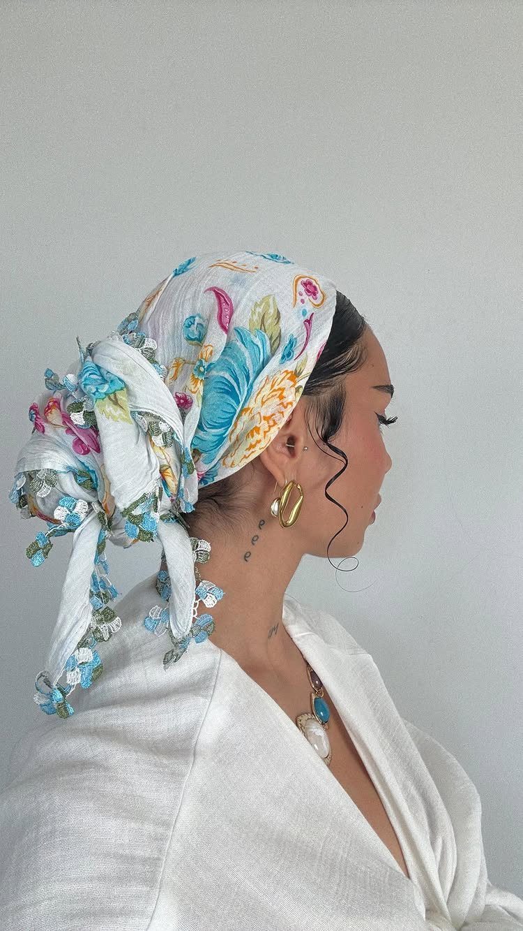 Woman in profile wearing a floral headscarf tied over a hair updo.