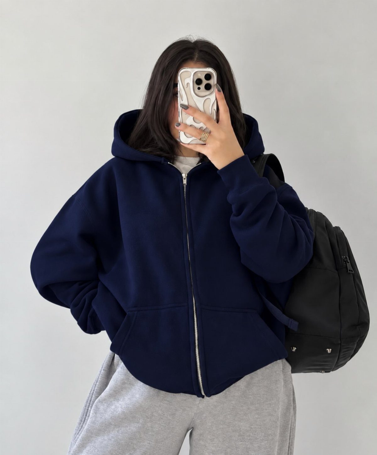 57 Degree Weather Outfit: 19 Ideas to Wear Now 6 Person wearing an oversized navy blue zip-up hoodie and grey sweatpants with a backpack.