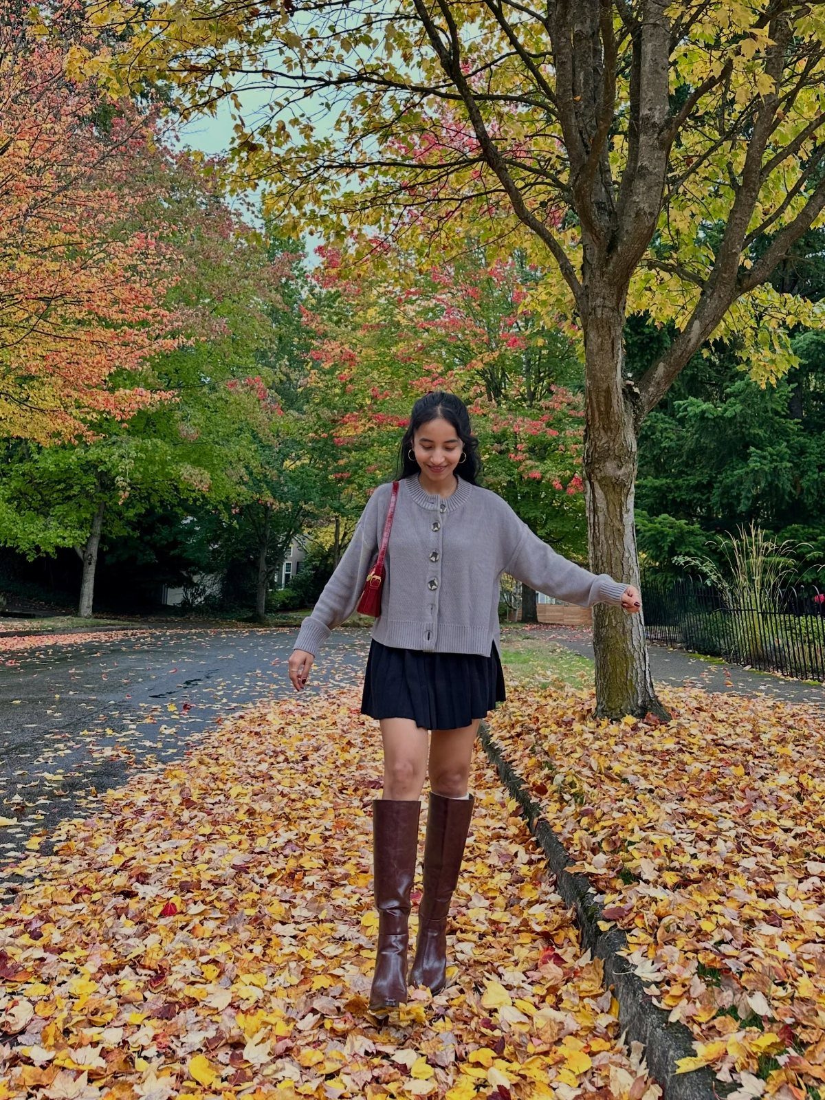 57 Degree Weather Outfit: 19 Ideas to Wear Now 12 Woman in grey cardigan and brown knee-high boots standing on autumn leaves.