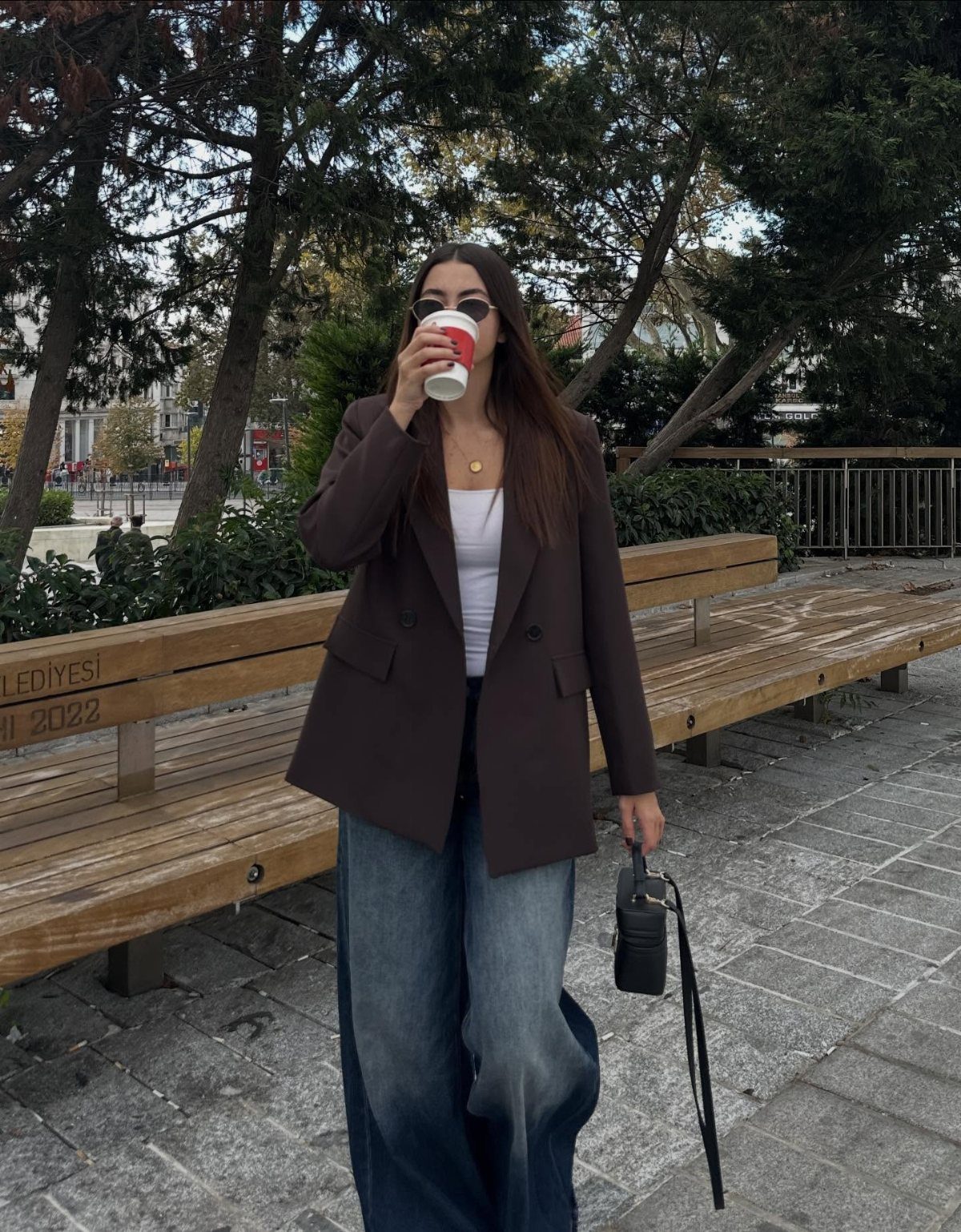 57 Degree Weather Outfit: 19 Ideas to Wear Now 10 Woman wearing a dark brown oversized blazer and wide-leg jeans standing outdoors.