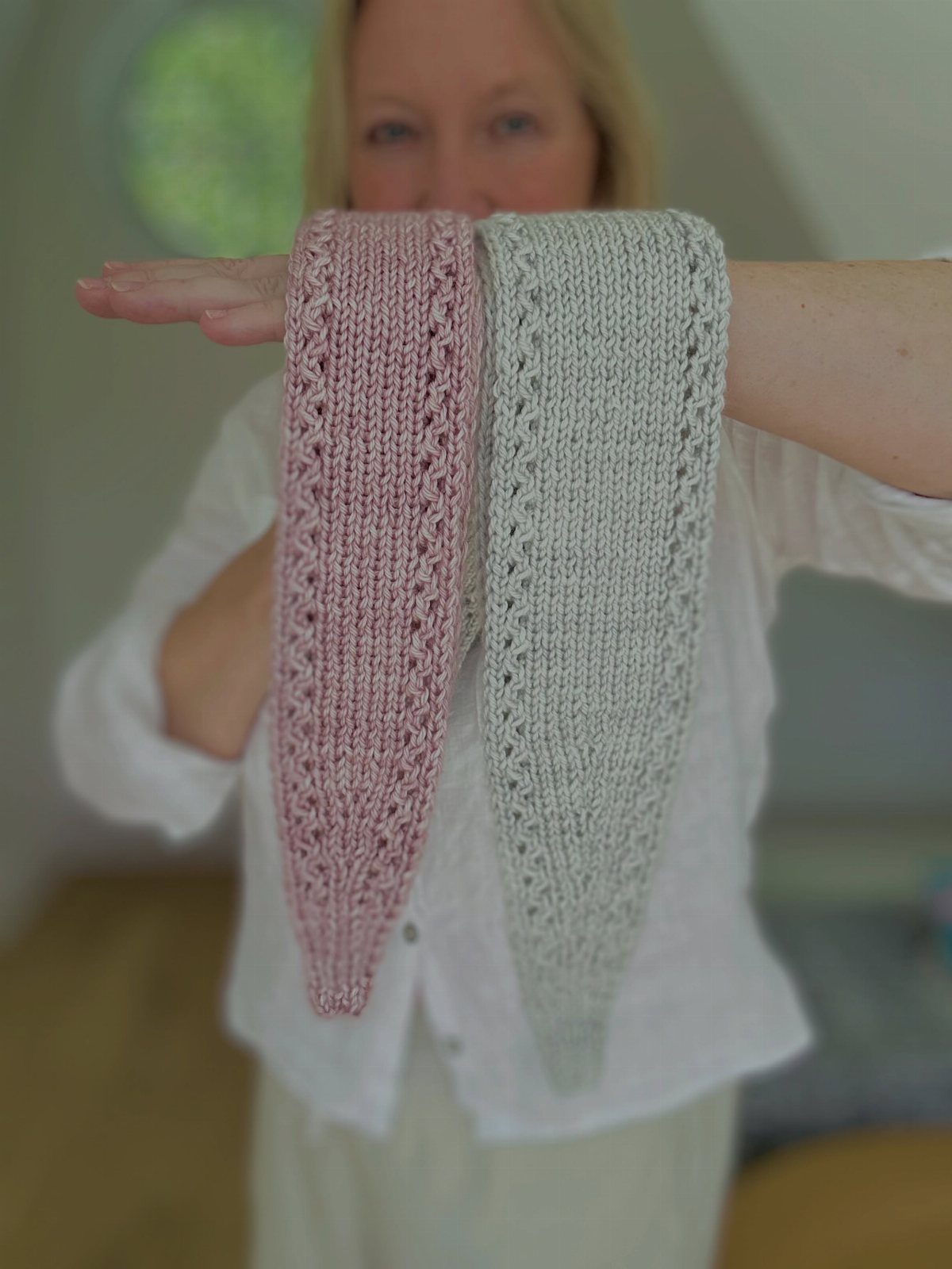 57 Degree Weather Outfit: 19 Ideas to Wear Now 16 Two knitted pointed scarves in pink and grey held up by a woman.
