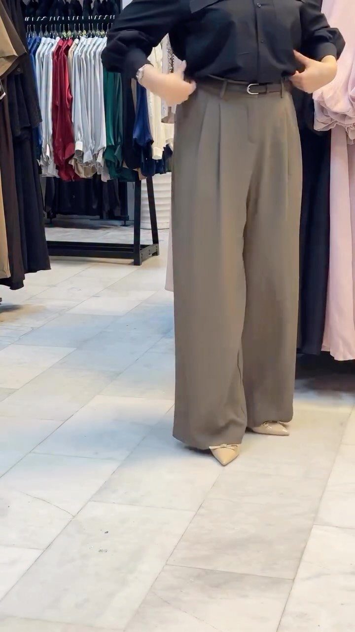 57 Degree Weather Outfit: 19 Ideas to Wear Now 15 Olive green wide-leg trousers paired with a black shirt in a clothing store.