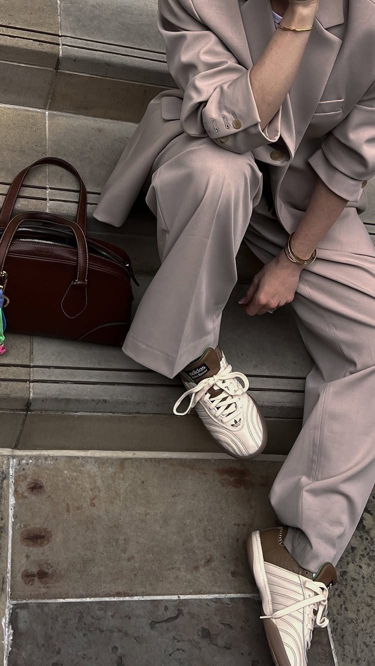 Adidas Outfit Shoes for 5 Casual and Dressed-Up Looks 5 Person in a beige suit wearing white Adidas sneakers sitting on stone steps.