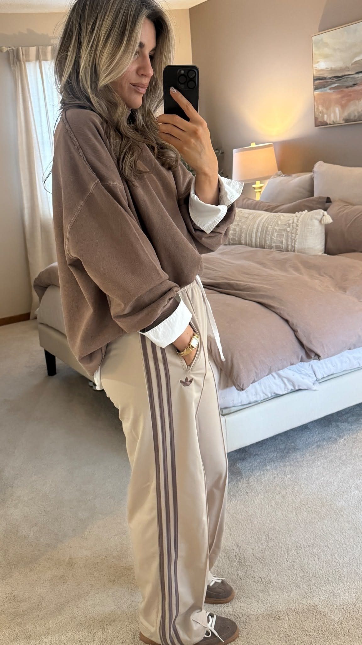 Adidas Outfit Shoes for 5 Casual and Dressed-Up Looks 1 Woman wearing a brown hoodie, beige Adidas track pants, and brown sneakers.
