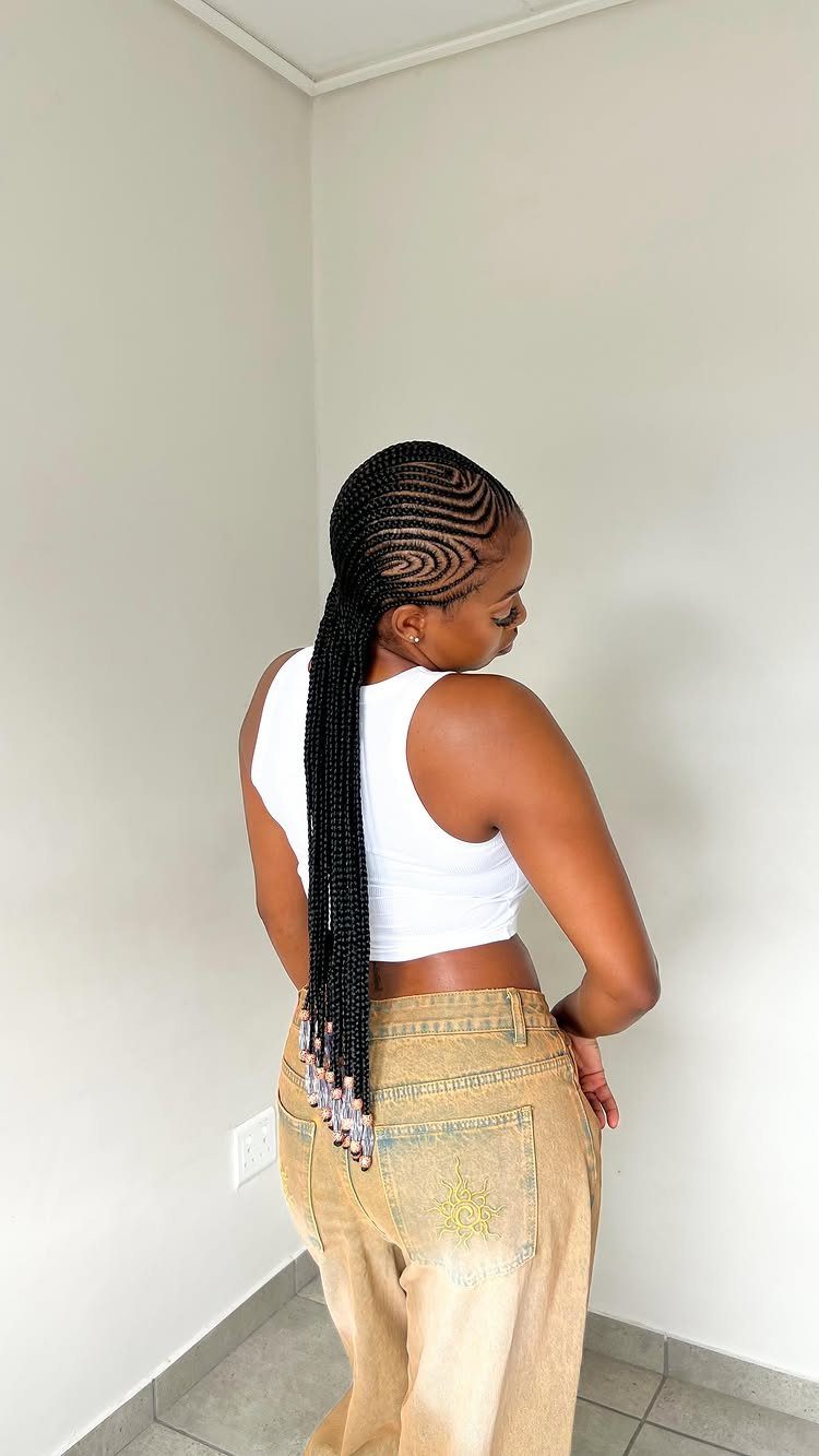 African Hair Lines: 10 Cornrow and Braid Styles to Wear 3 Woman with curved cornrow braids gathered into a long beaded ponytail