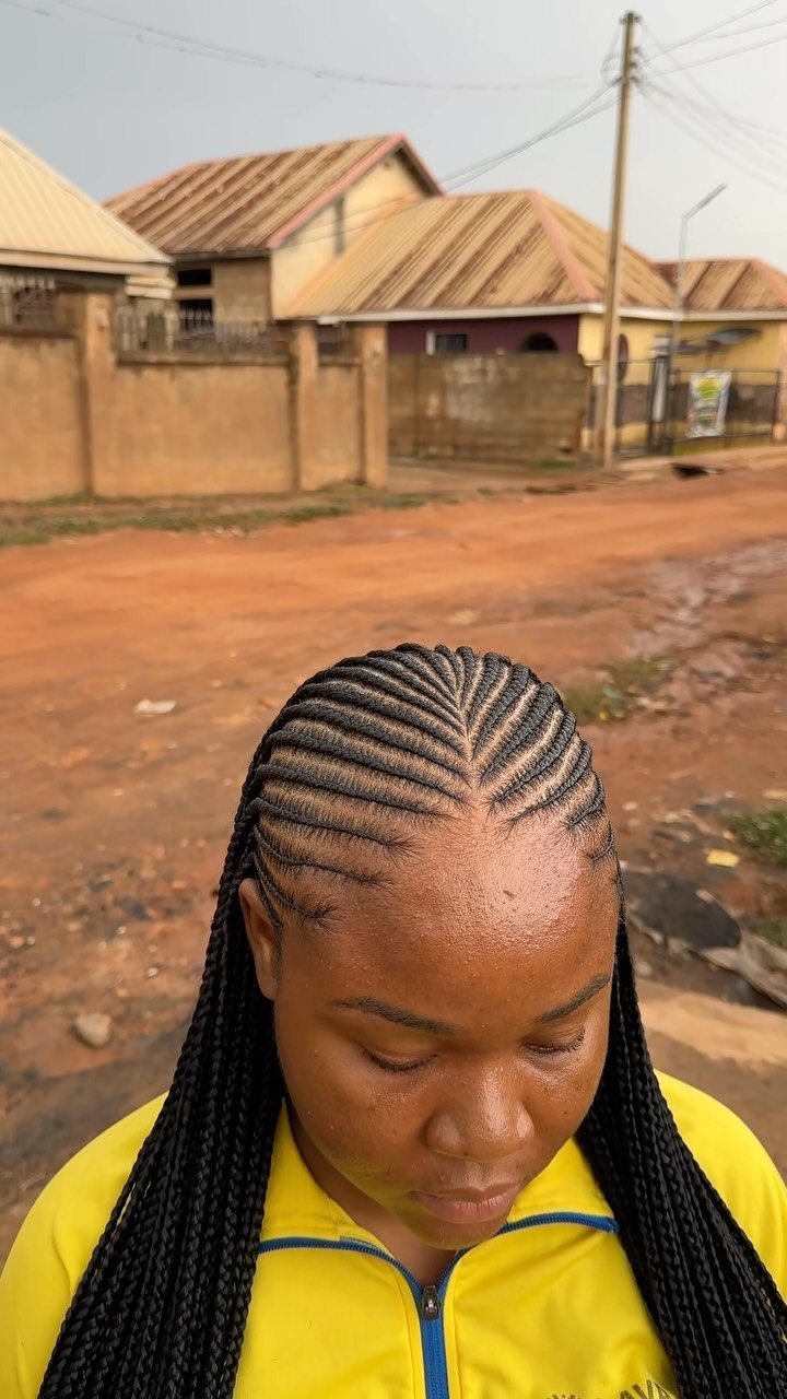 African Hair Lines: 10 Cornrow and Braid Styles to Wear 1 Woman with straight-back cornrows wearing a yellow jacket on a dirt road.