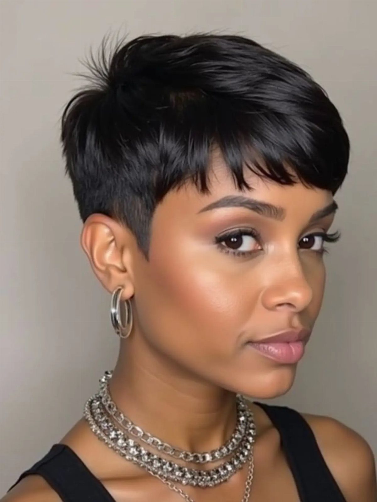 7 Back Hairstyle for Women Ideas, Braids to Buns 6 Woman with a sleek, dark pixie cut hairstyle and silver jewelry.