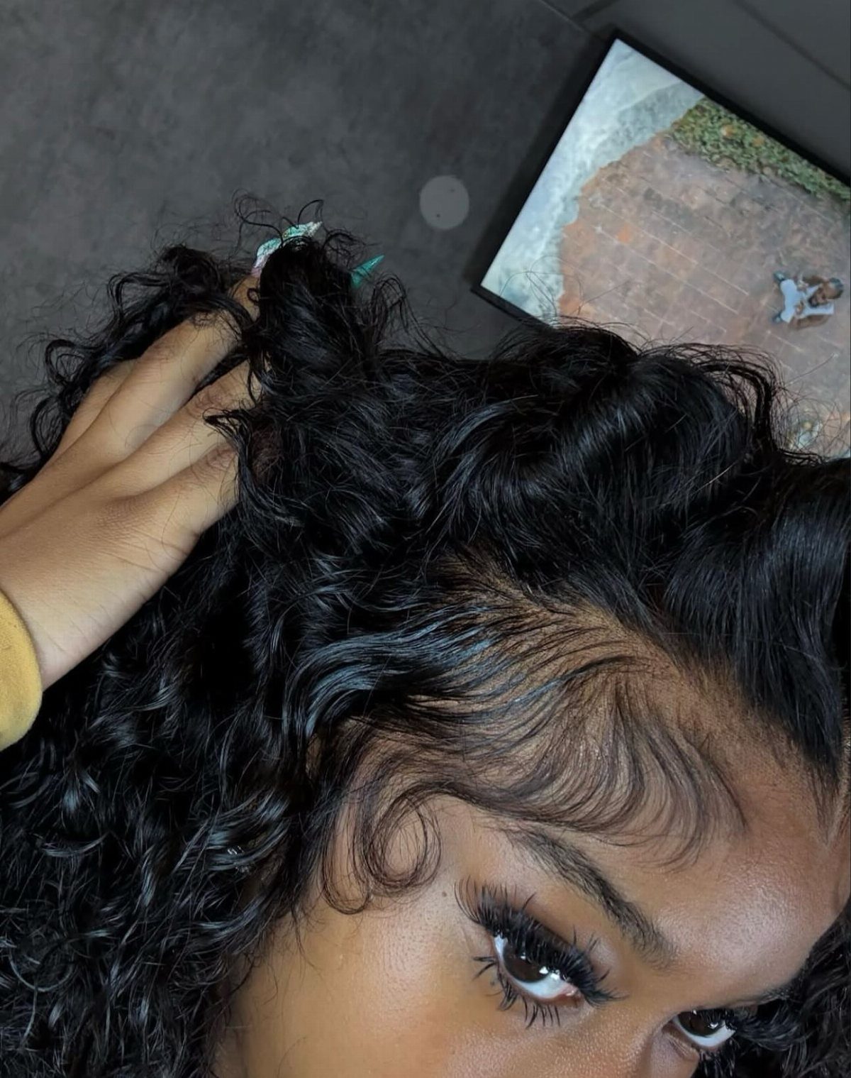 Woman with voluminous black curly hair and meticulously styled, laid edges along her hairline.