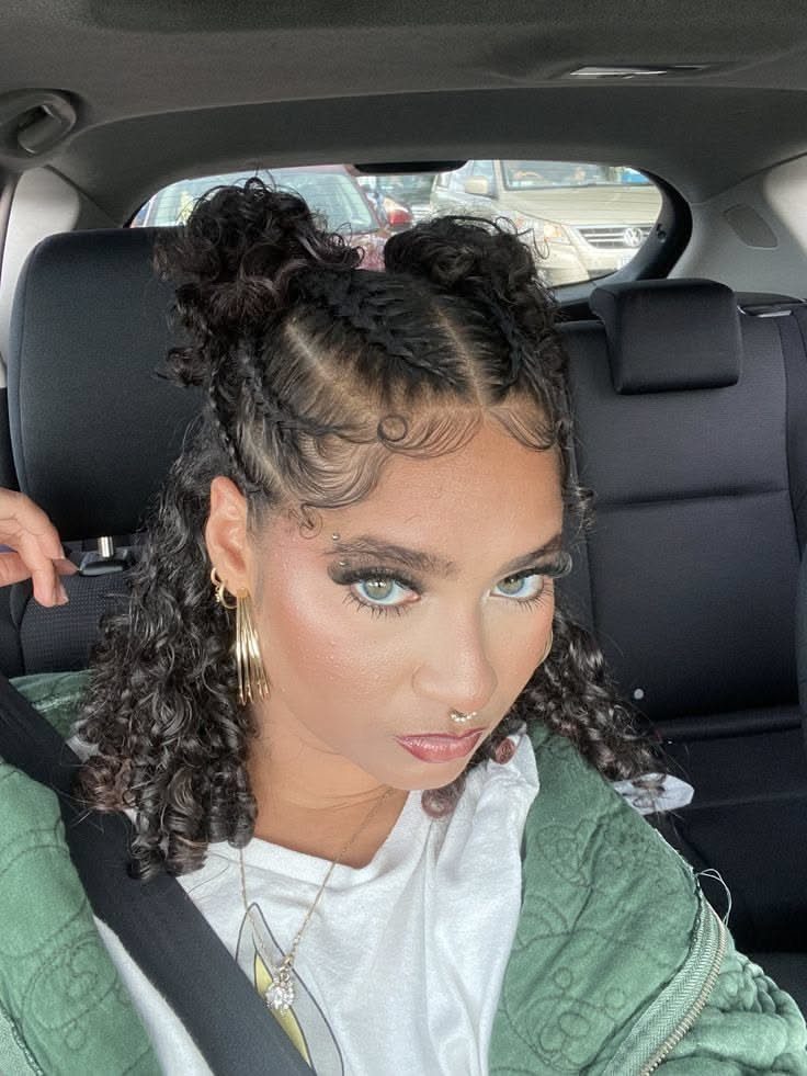 Woman with dark curly hair styled in two high buns and laid edges.