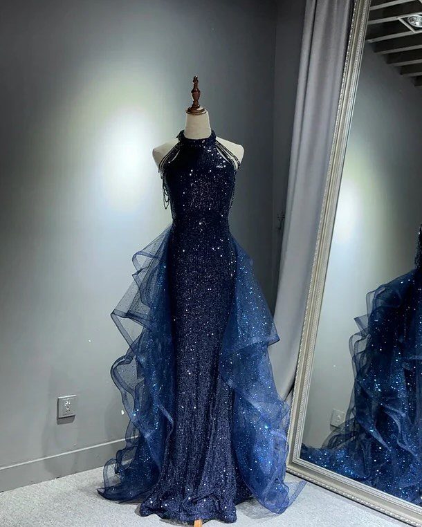 Ball Dresses Blue for Prom and Formal Events: 10 Ideas 1 Navy blue glittery gown with a ruffled tulle overskirt on a mannequin.