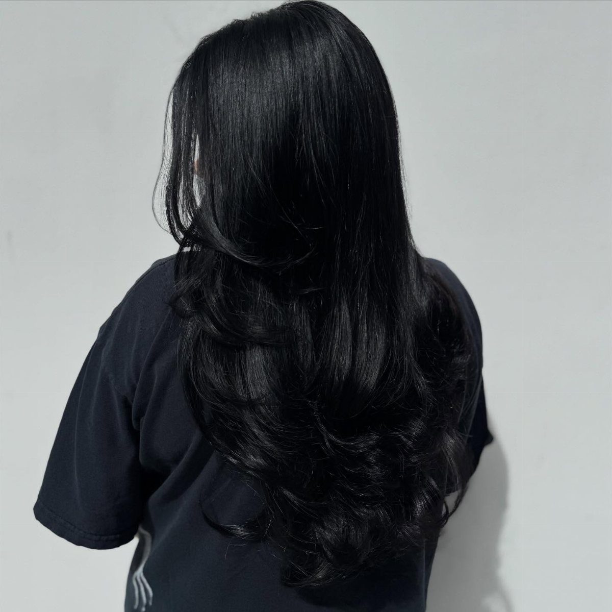 Best Hair Dye for Dark Hair: 8 Shades and Ideas 2 Long wavy black hair seen from behind against a plain gray background