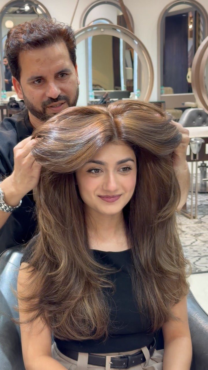 Best Hair Dye for Dark Hair: 8 Shades and Ideas 8 Woman with voluminous brown highlighted hair being styled by a man in a salon
