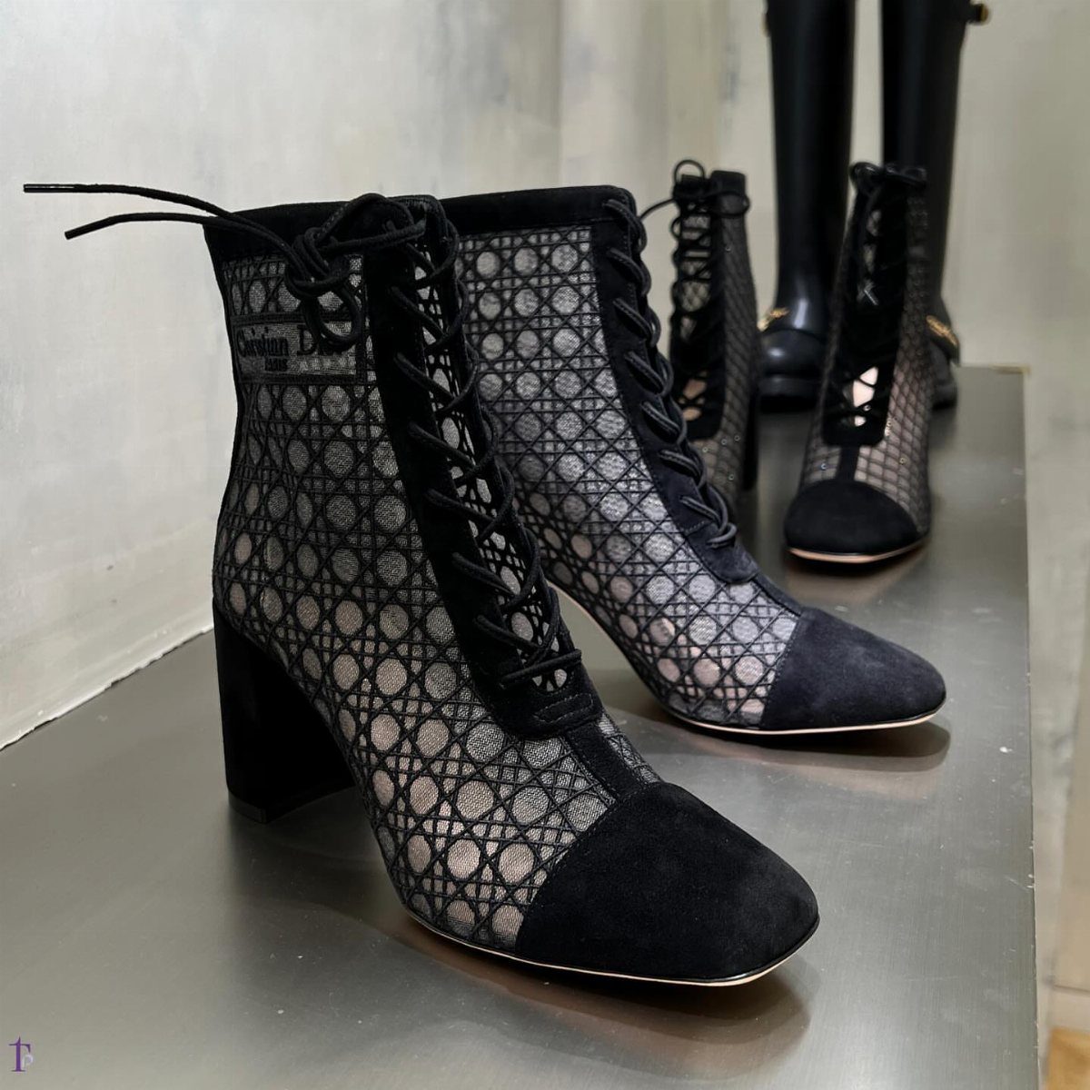 Black lace-up ankle boots with sheer quilted pattern and suede toes on grey surface