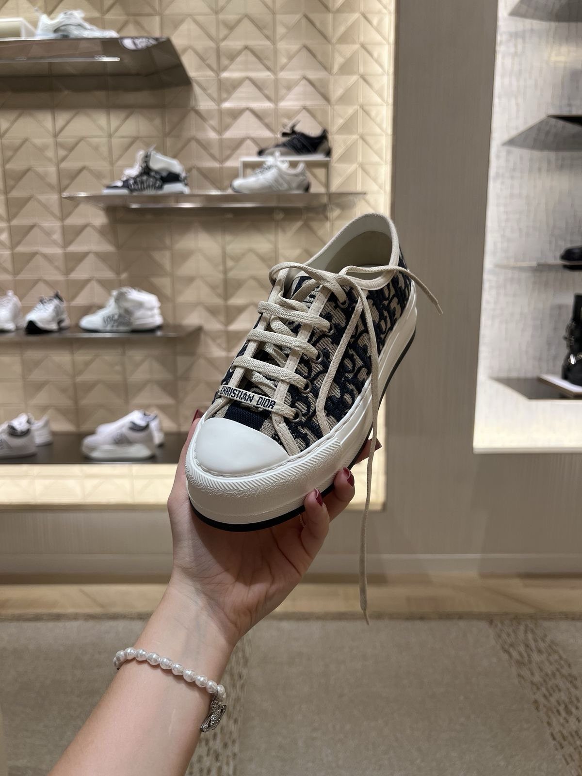 Dior Walk'n'Dior sneakers with oblique pattern held in a hand inside a store