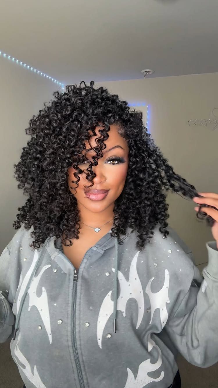 17 Black Natural Hair Ideas for Every Length and Style 14 Woman with voluminous curly black natural hair and curly bangs wearing a grey hoodie.
