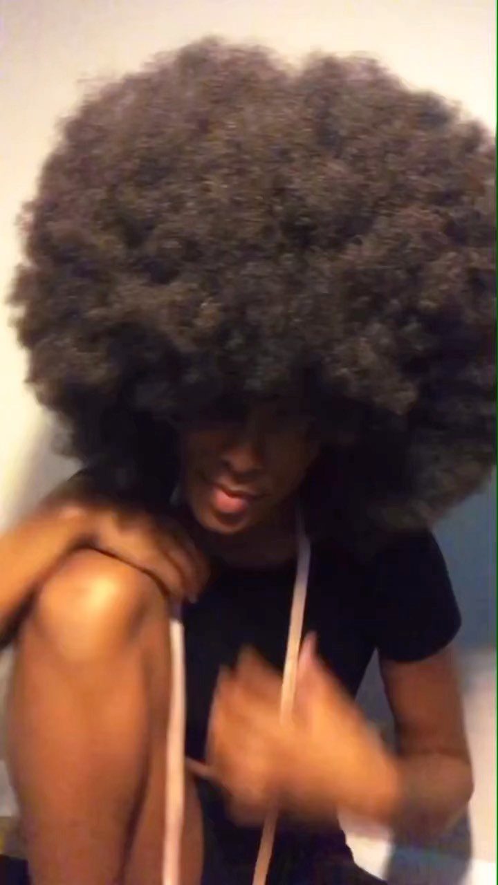 17 Black Natural Hair Ideas for Every Length and Style 6 Person with a large, voluminous black natural afro hairstyle wearing a black shirt.