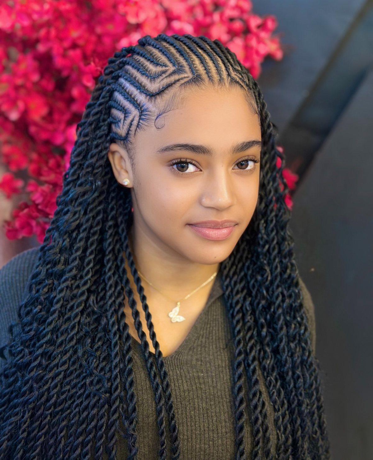 17 Black Natural Hair Ideas for Every Length and Style 1 Young woman with long black braids and intricate geometric scalp patterns and pink flowers.