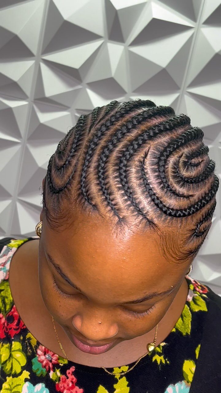 17 Black Natural Hair Ideas for Every Length and Style 5 Black woman with intricate curved cornrow braids against a white geometric wall
