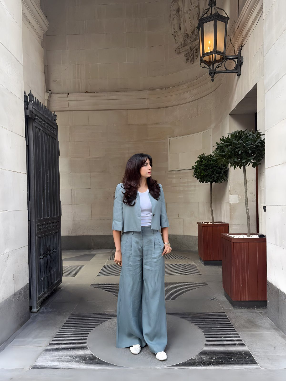 Blue Blazer Outfit for Women: 24 Ideas to Wear 19 Woman wearing a light blue cropped blazer and matching wide-leg trousers in a courtyard