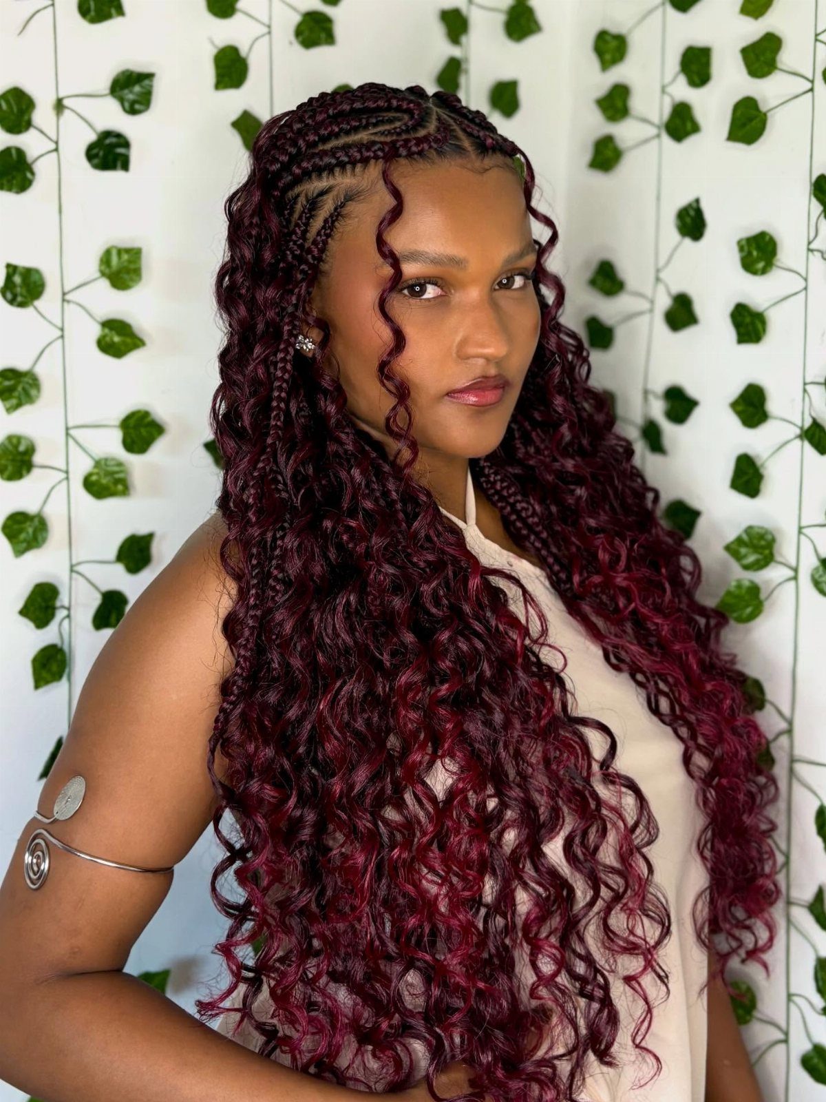 27 Boho Fulani Braids Hairstyles for Every Length and Look 1 Woman with long burgundy-red Fulani braids and curly ends against ivy background