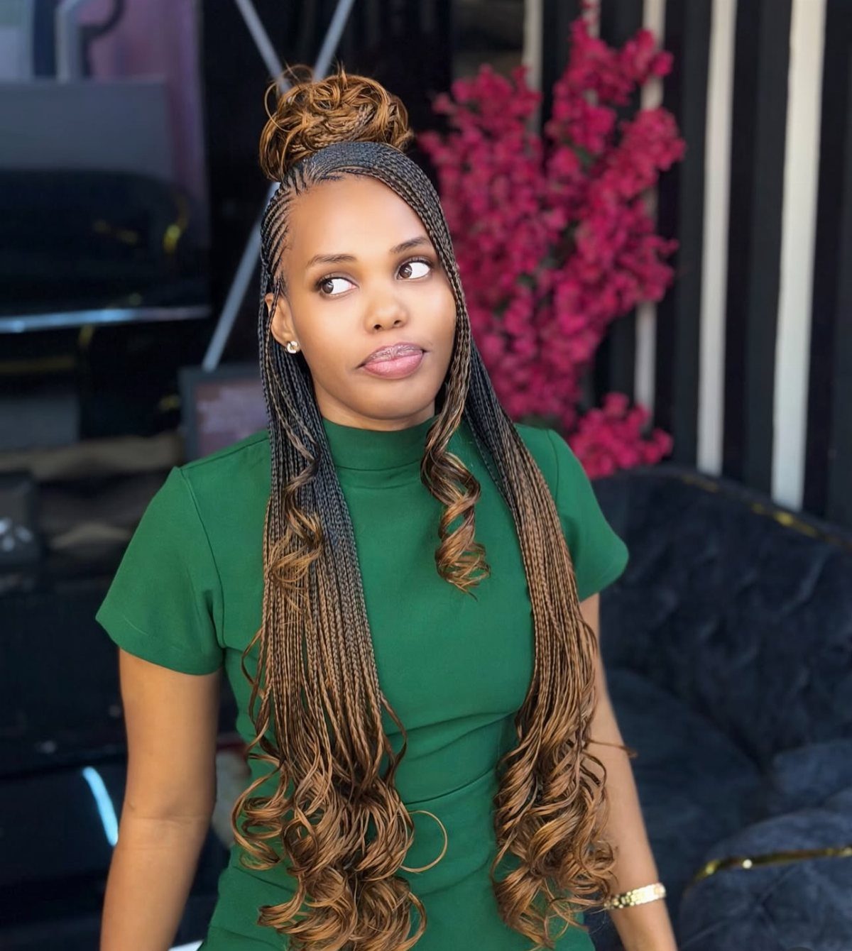 27 Boho Fulani Braids Hairstyles for Every Length and Look 11 Woman with brown Fulani braids styled in a high bun and curly ends.