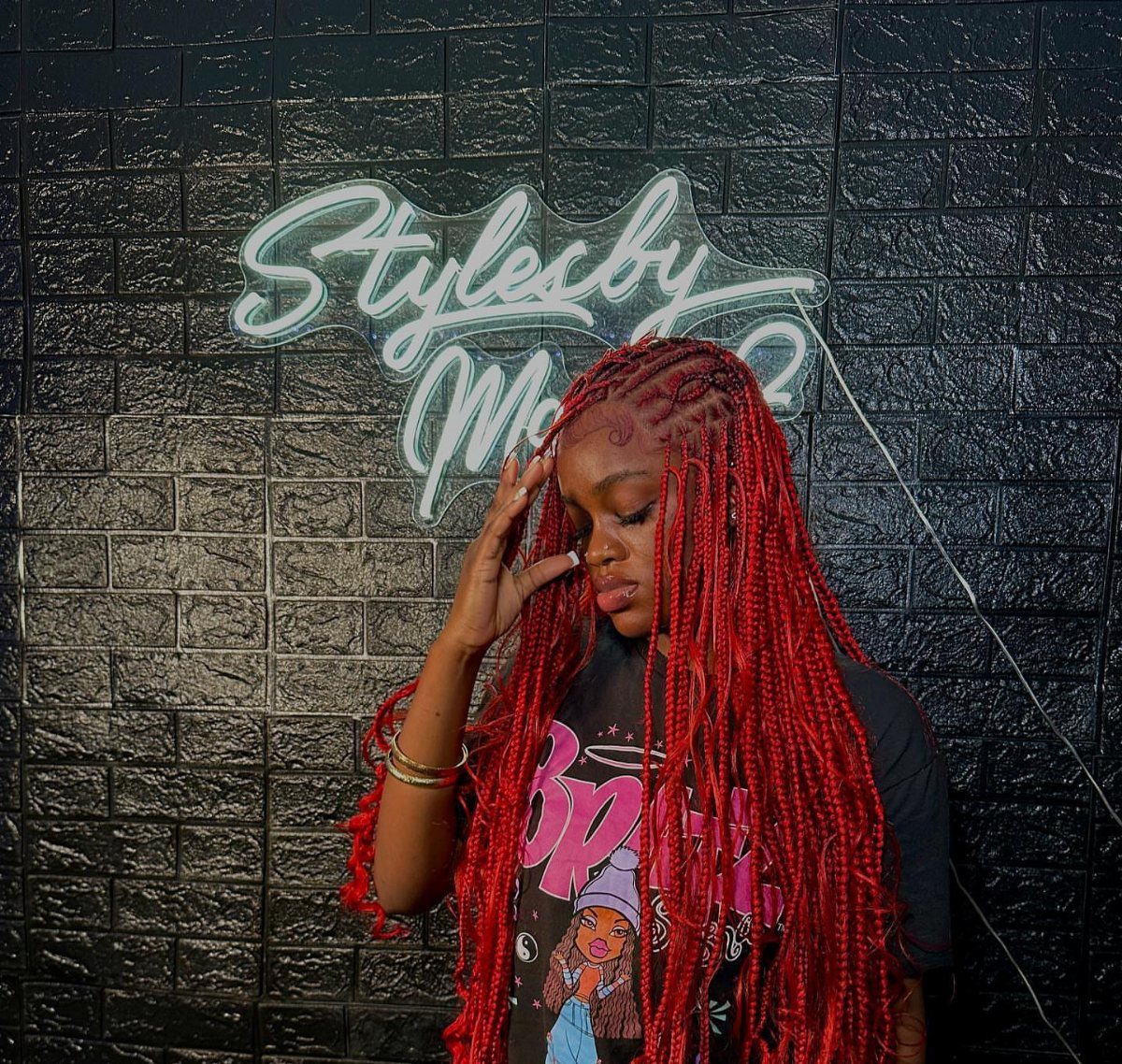 27 Boho Fulani Braids Hairstyles for Every Length and Look 9 Woman with long red Fulani braids posing against a black brick wall.