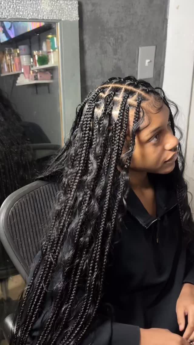 Person with long black boho knotless box braids and curly loose hair strands.