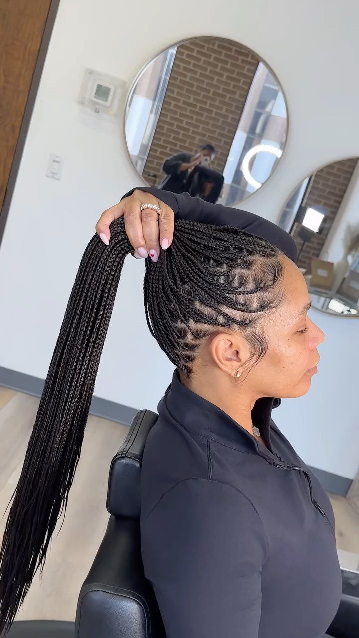 Woman with black box braids gathered into a high ponytail in a salon