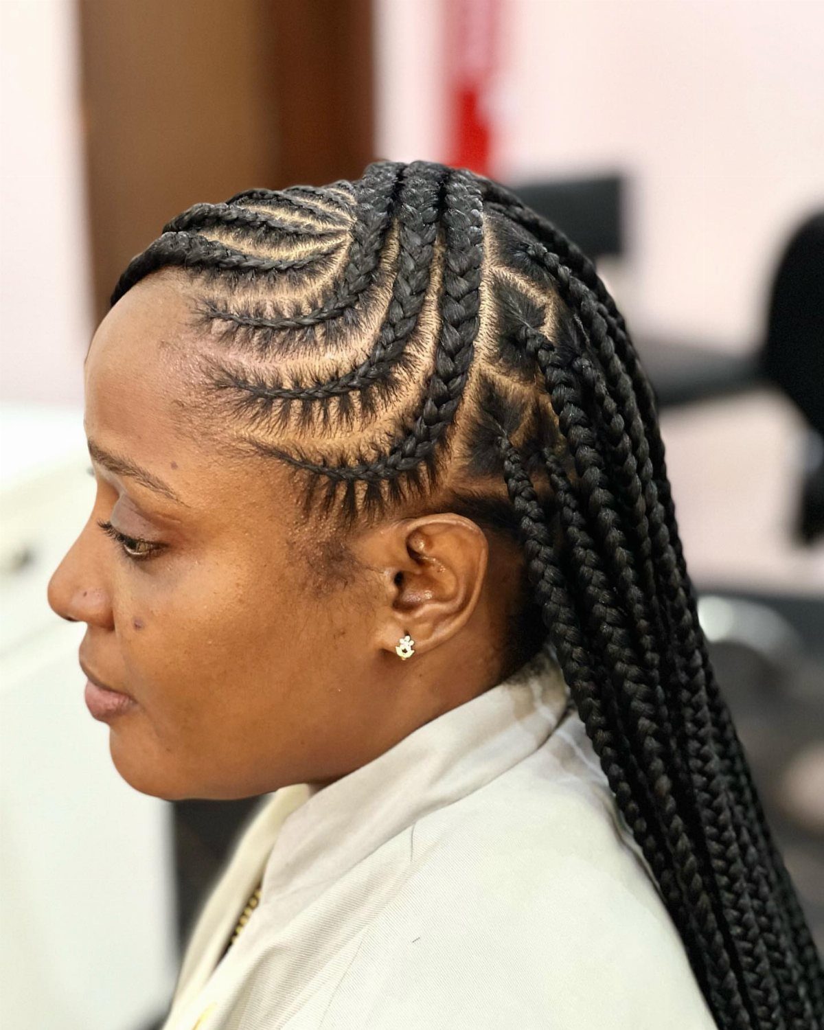 Woman with black cornrows transitioning into long box braids in a side profile