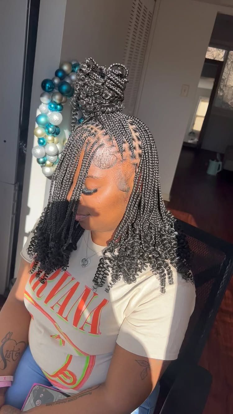 Woman with black box braids styled in a half-up high bun hairstyle.
