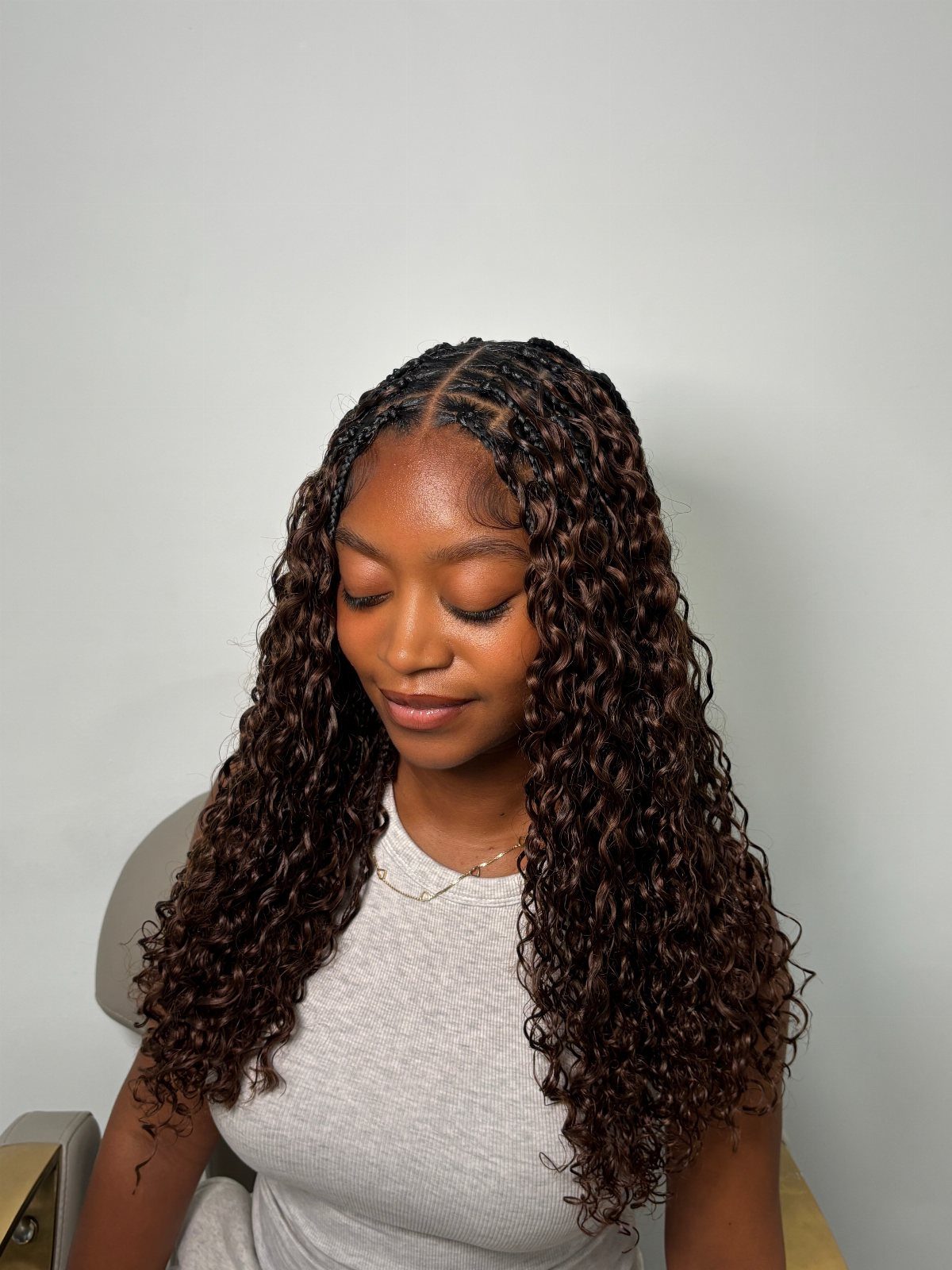 20 Braids and Women Hairstyles to Try in 2026 13 Woman with long curly brown crochet braids and braided roots wearing grey top