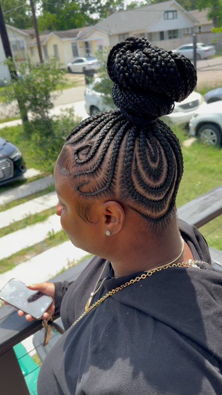 20 Braids and Women Hairstyles to Try in 2026 10 Woman with curved cornrows gathered into a large braided bun on top.