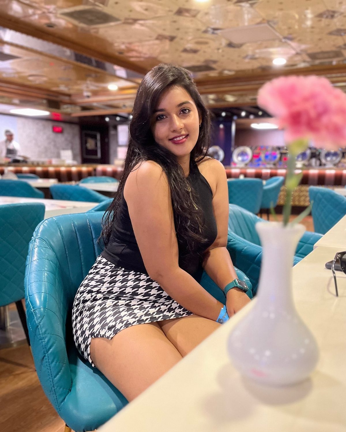 Woman in black top and houndstooth mini skirt sitting in a blue casino chair.