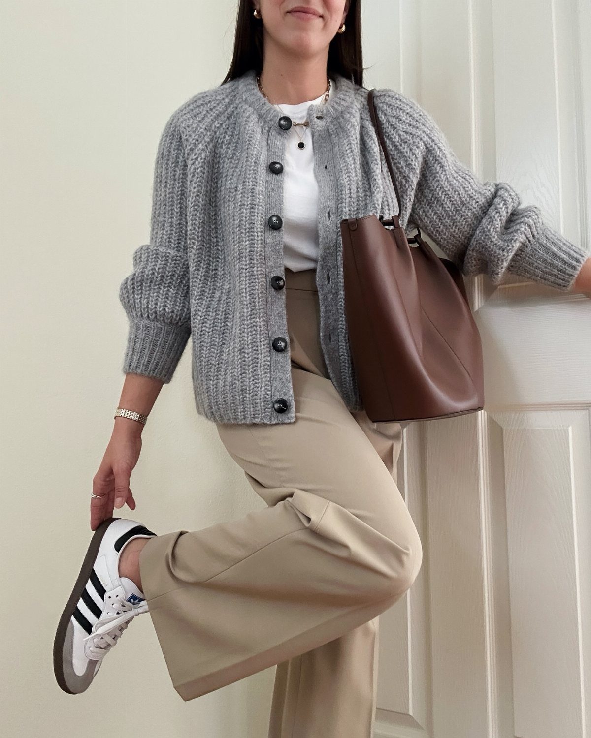 12 Casual Elegance Outfits for Easy Everyday Style 12 Person in grey cardigan and beige wide-leg trousers carrying a brown leather tote bag.