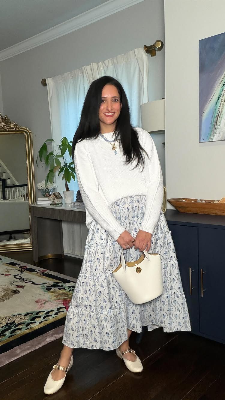 12 Casual Elegance Outfits for Easy Everyday Style 2 Woman wearing a white sweater over a floral midi dress with white flats.