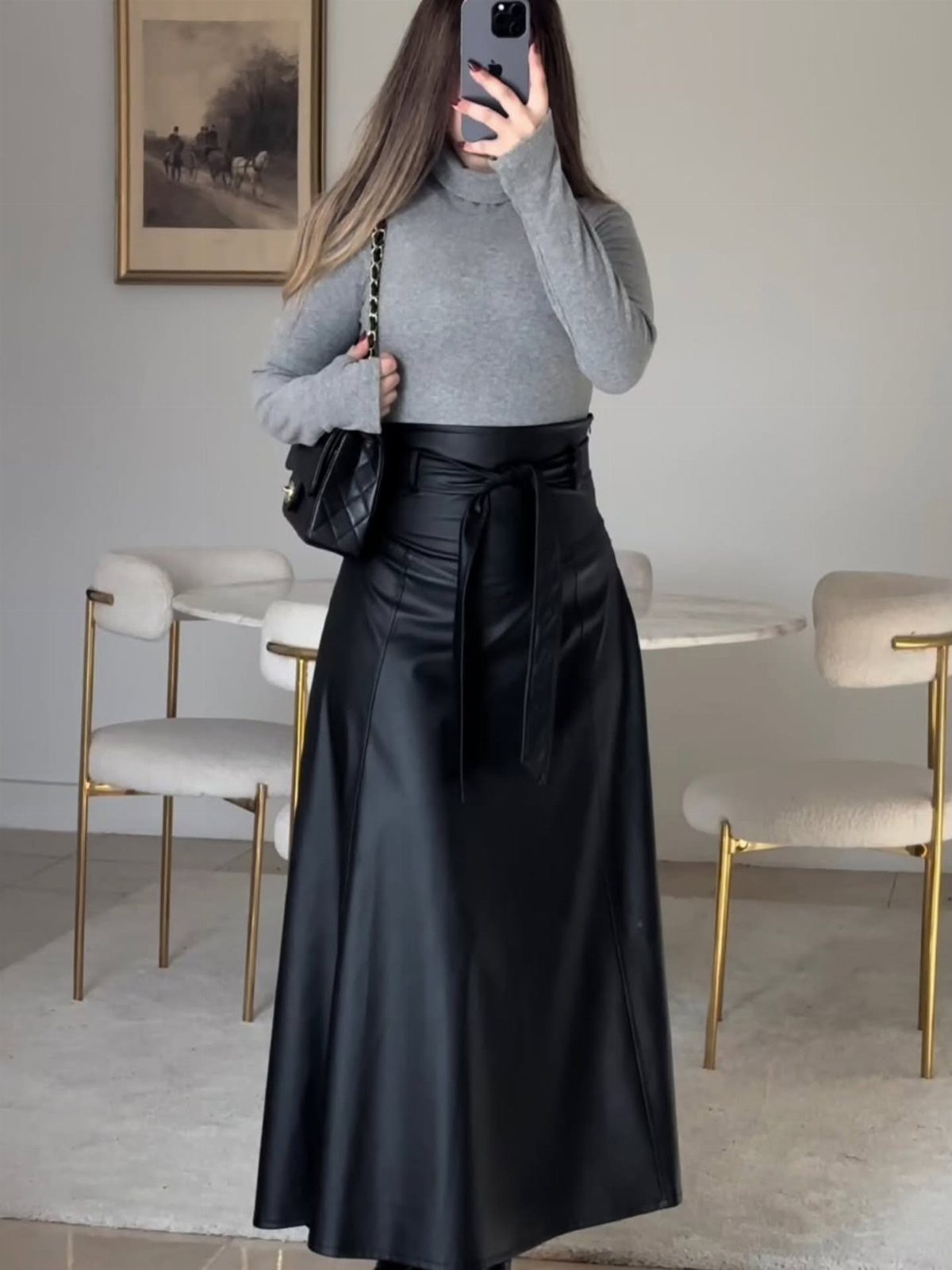 Christmas Outfit for Work: 13 Ideas to Wear to the Office 8 Person wearing a grey turtleneck and long black faux leather belted skirt.