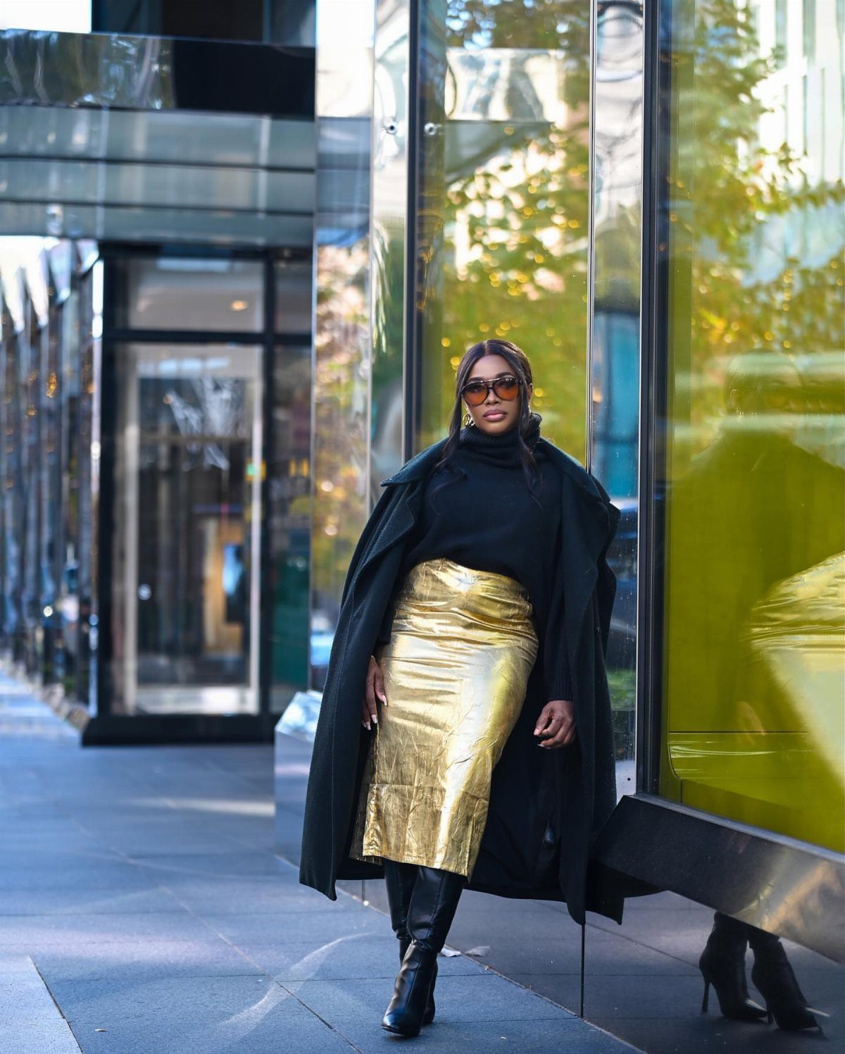 Christmas Outfit for Work: 13 Ideas to Wear to the Office 2 Woman wearing a gold metallic midi skirt and black coat on a city street.