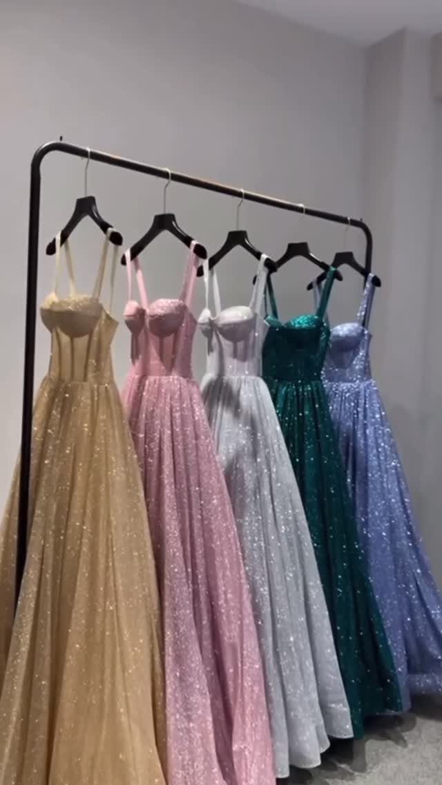 Classic Formal Gowns: 8 Styles for Evening Events 5 Five shimmering floor-length evening gowns in various colors hanging on a black rack.
