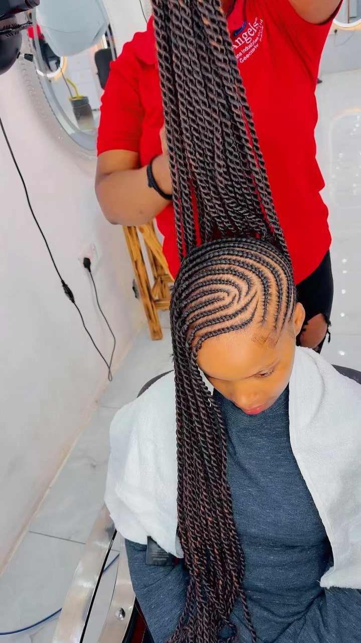 Cornrows and Twists Hairstyles: 11 Ideas to Try 6 Woman with curved cornrows and long twists being held up by a stylist.