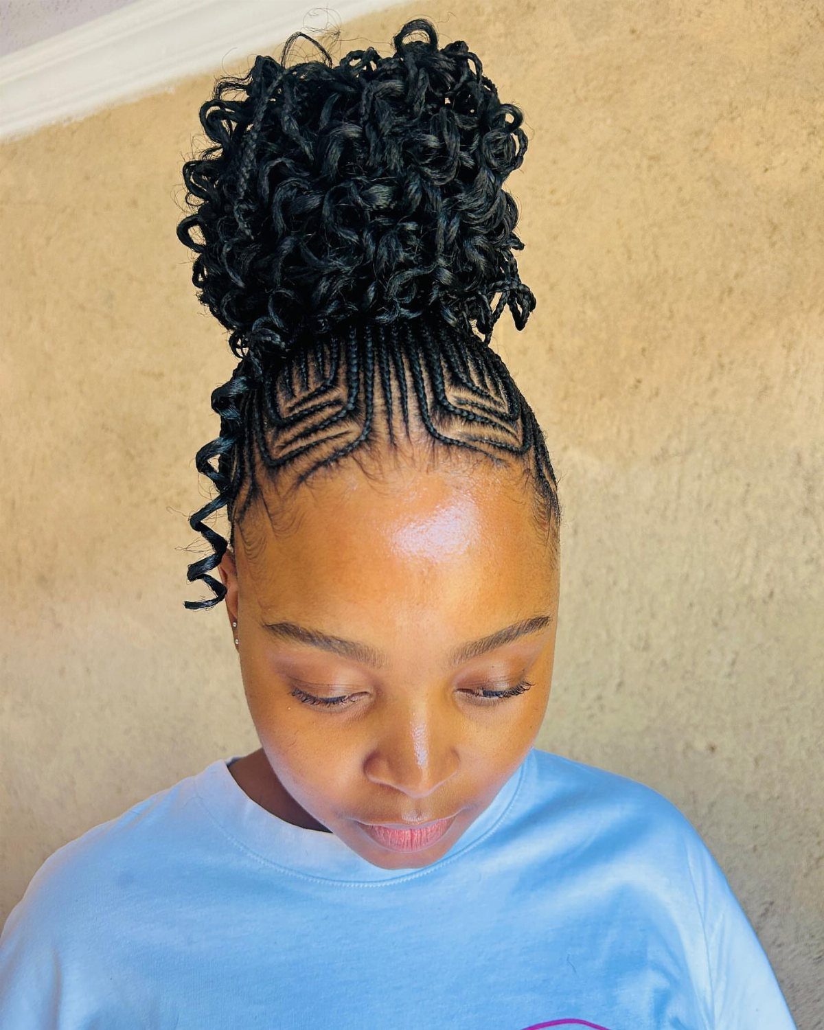 Cornrows and Twists Hairstyles: 11 Ideas to Try 4 Woman with cornrow braids gathered into a large, curly high bun hairstyle.