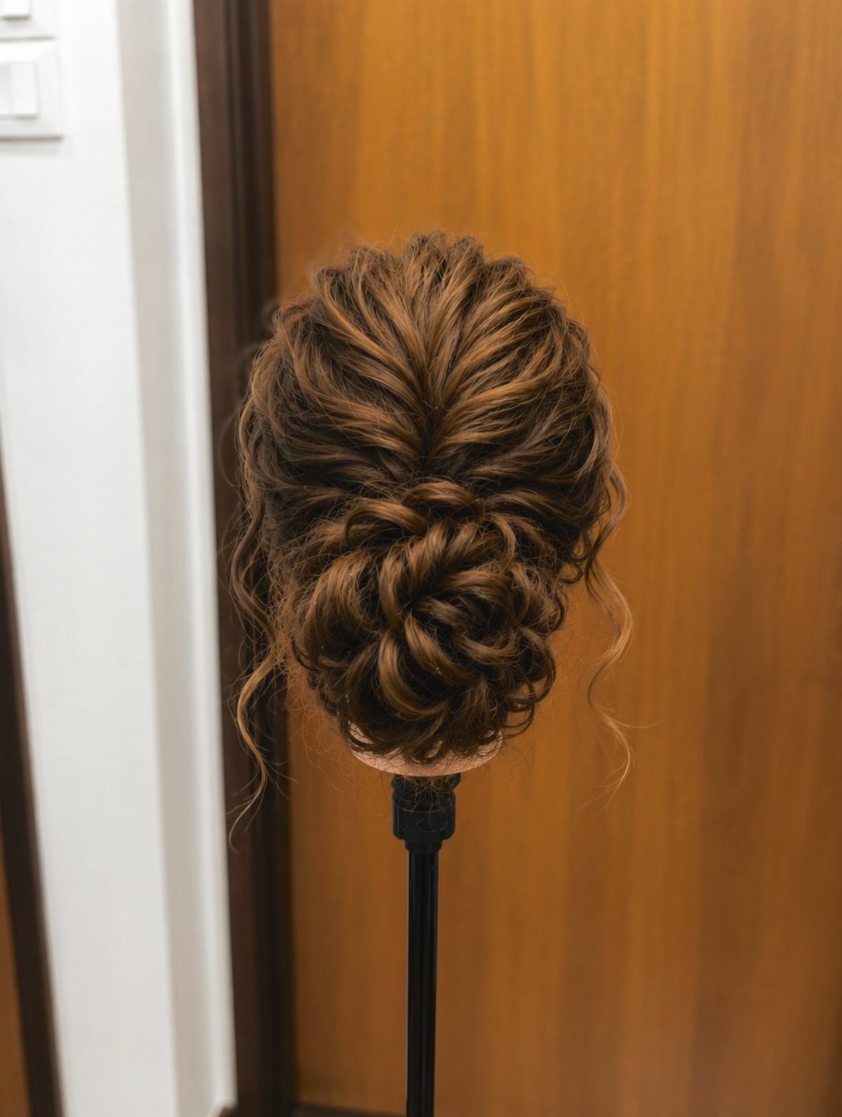 Intricate twisted curly bun hairstyle on a brown hair mannequin head