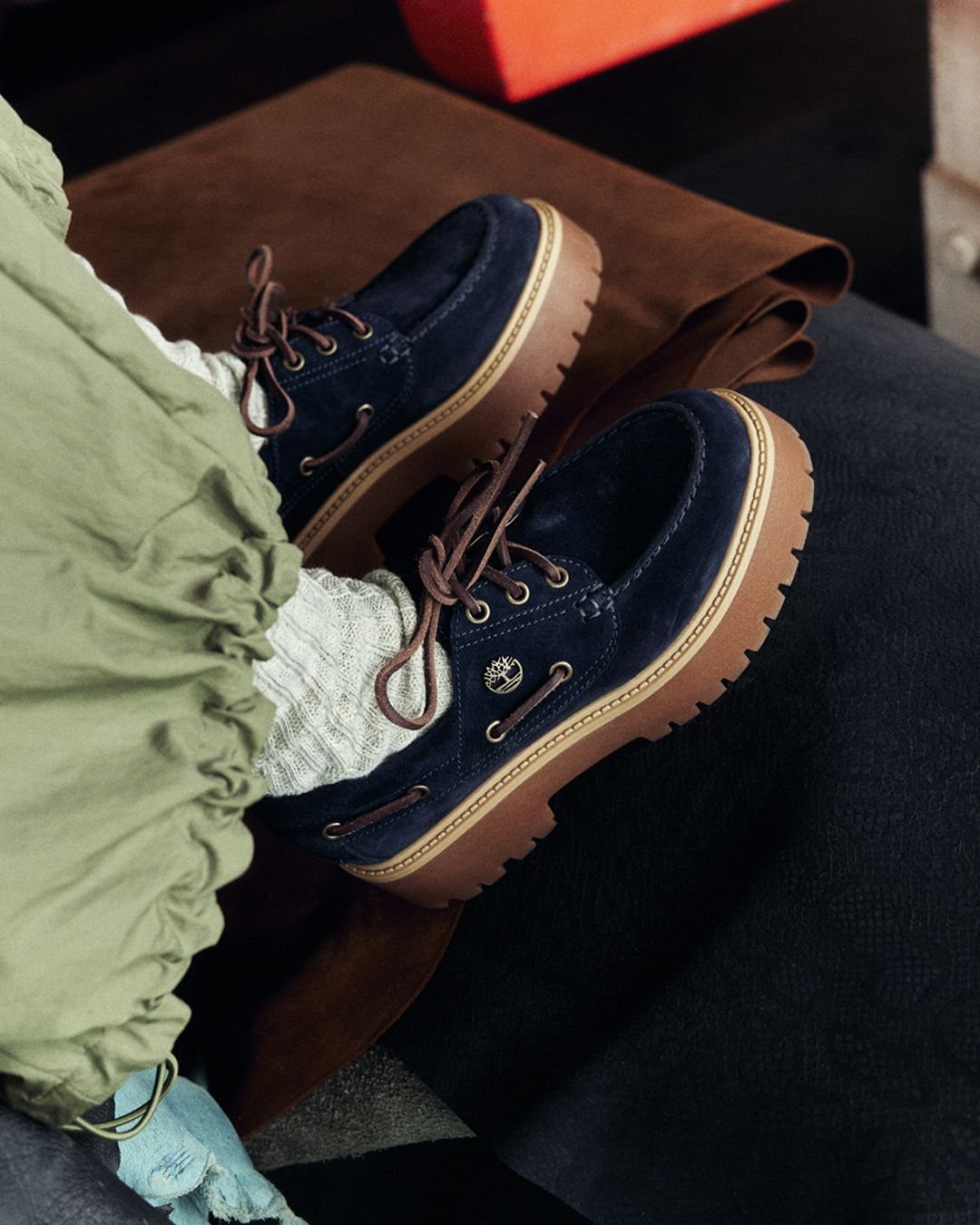 Dark blue suede Timberland boots with brown soles worn with olive green trousers.