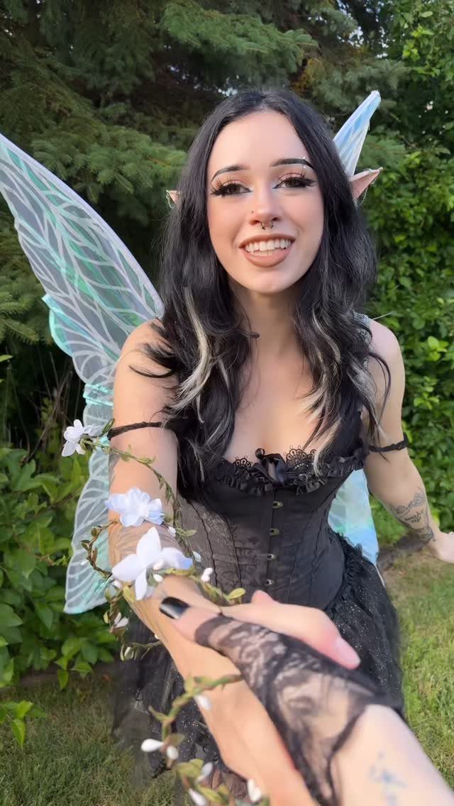 Woman in dark fairy costume with wings, black corset, and floral arm vines.