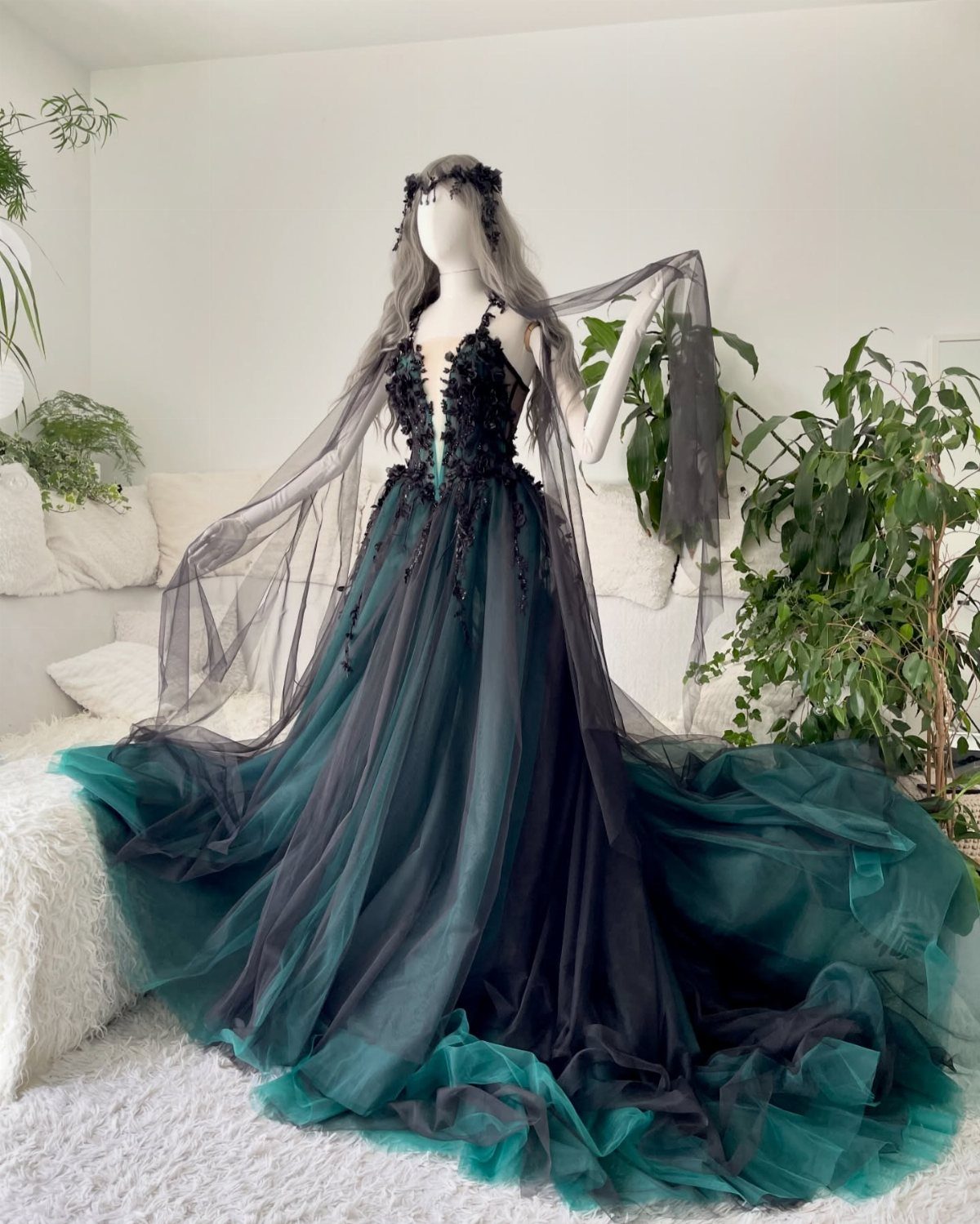 Dark teal and black layered tulle gown on a mannequin with sheer cape